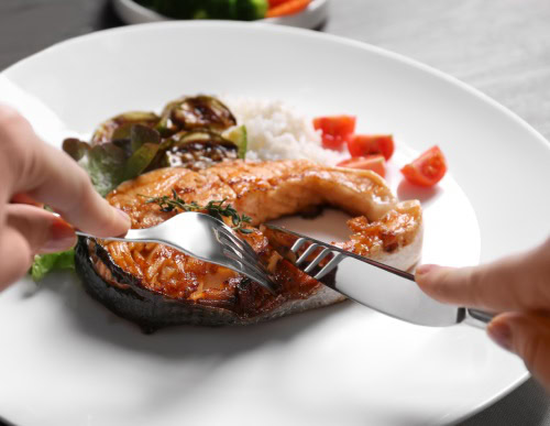 Peixe sendo fatiado num prato branco.