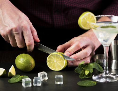 Homem fatiando o limão para colocar no drink.