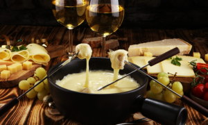 Queijo derretido em panela com uvas verdes, queijo, vinho branco e ingredientes para fondue, ideal para refeições especiais e momentos de confraternização.
