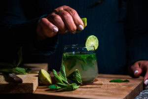 mão finalizando copo de mojito demonstrando como fazer mojito