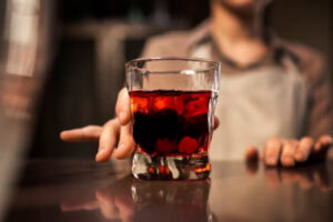 copo de drinks com campari em destaque com homem em blur atras