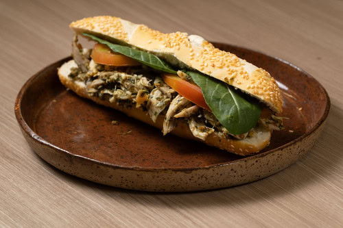 Sanduíche de frango com pesto e salada de rúcula.