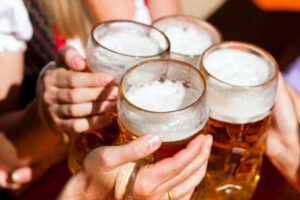 Pessoas brindando com canecas de chopp.