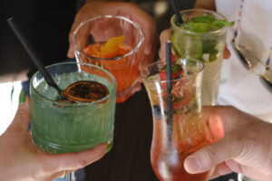 Quatro mãos segurando diferentes drinks.