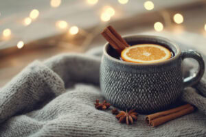 Caneca com quentão, rodela de laranja e pedaço de canela.