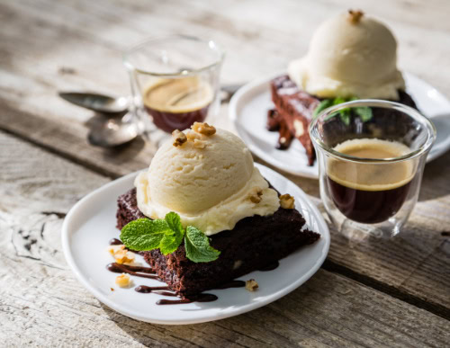 Brownie com sorvete de creme em cima e café ao lado.