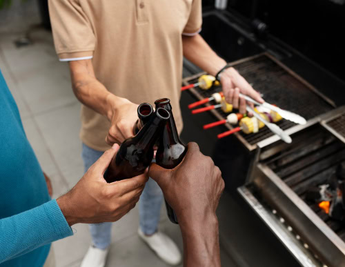 Três amigos brindando com cerveja em churrasco.