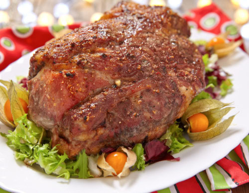 Pernil de Natal em prato branco com salada.